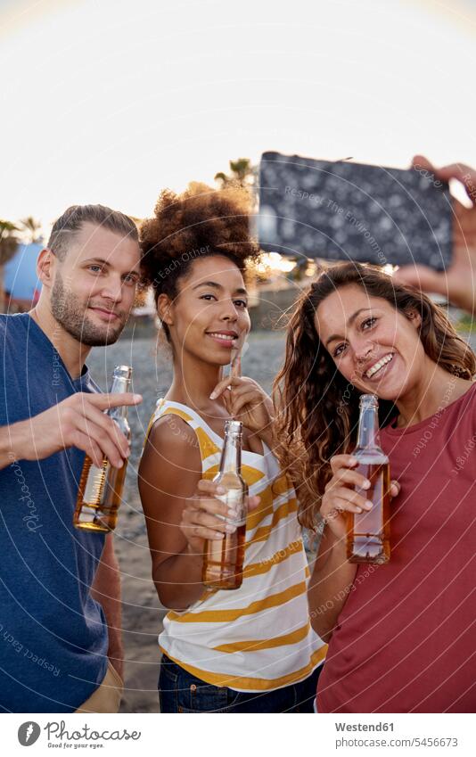 Drei Freunde mit Bierflaschen machen ein Selfie am Strand Beach Straende Strände Beaches Selfies Alkohol Alkoholische Getraenke Alkoholisches Getränk