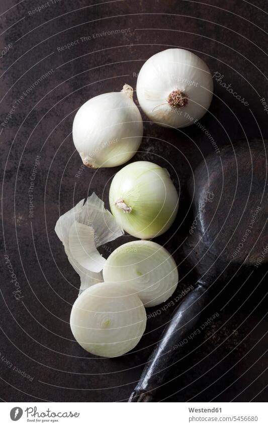 Geschnittene und ganze weiße Zwiebeln auf rostigem Boden weißes weißer weiss aufgeschnitten Scheibe angeschnitten Stück Stücke Scheiben Zwiebelschale