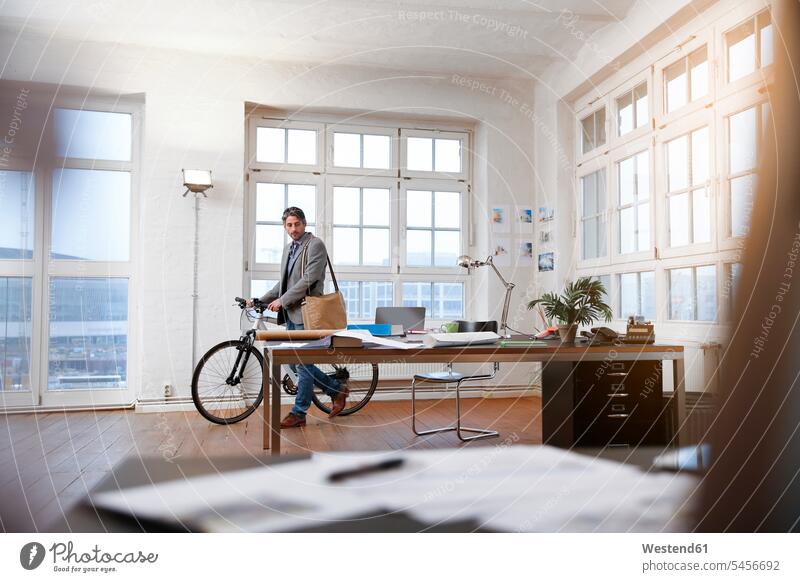 Mann mit Fahrrad in einem modernen informellen Büro Männer männlich Bikes Fahrräder Räder Rad Office Büros Geschäftsmann Businessmann Businessmänner