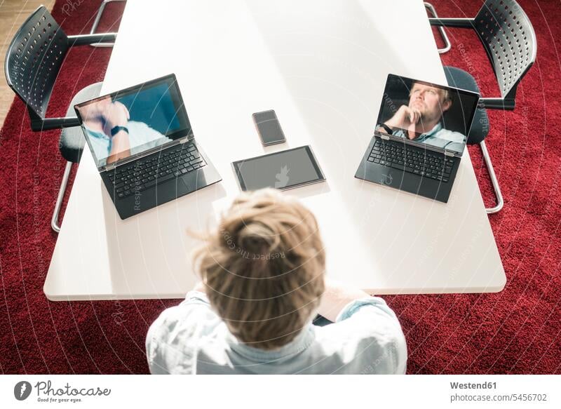 Geschäftsmann mit zwei Laptops, die Bilder von sich selbst zeigen Foto Fotos Businessmann Businessmänner Geschäftsmänner Notebook Notebooks Büro Office Büros