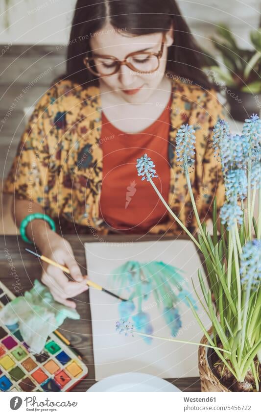 Junge Frau malt Pflanzen mit Wasserfarben Pinsel Traubenhyazinthe Muscari Traubenhyazinthen malen zeichnen Zeichnung Aquarell junge Frau junge Frauen weiblich
