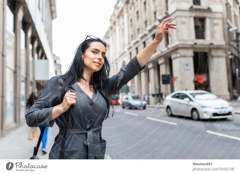Frau in der Stadt, die ein Taxi ruft, London, Großbritannien Leute Menschen People Person Personen Europäisch Kaukasier kaukasisch 1 Ein ein Mensch eine