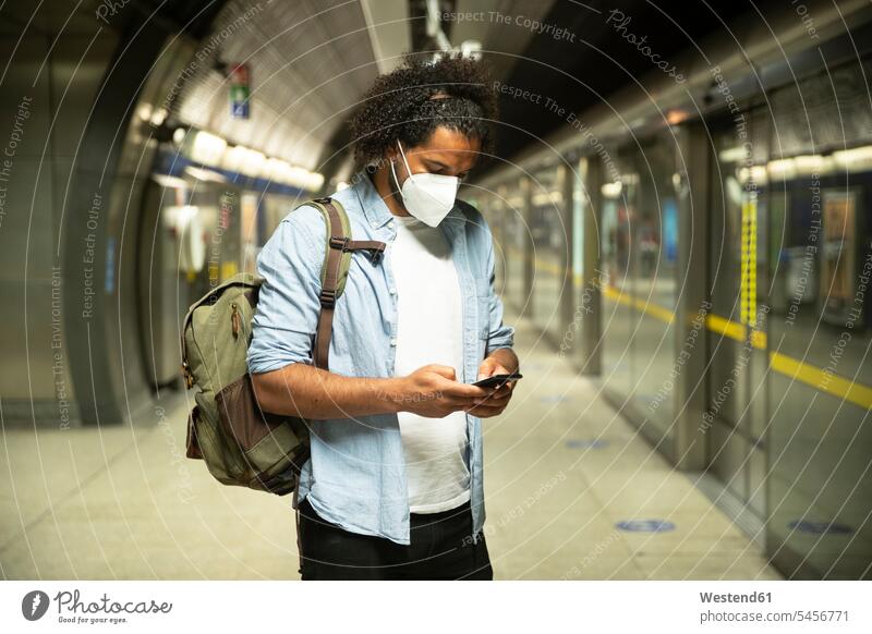 Junger Mann mit Schutzmaske am U-Bahn-Bahnsteig, London, Großbritannien Rucksäcke Informationen Transport Transportwesen Bahnen Subway U-Bahnen Ubahn Ubahnen