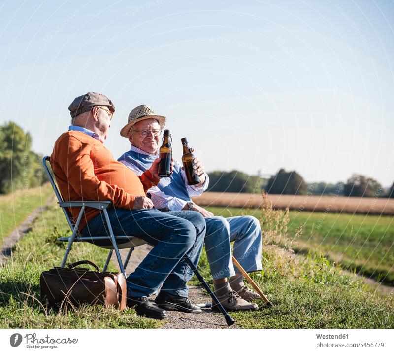 Zwei alte Freunde sitzen auf den Feldern, trinken Bier und reden über alte Zeiten Beste Freunde Bester Freund sprechen sitzend sitzt Alkohol