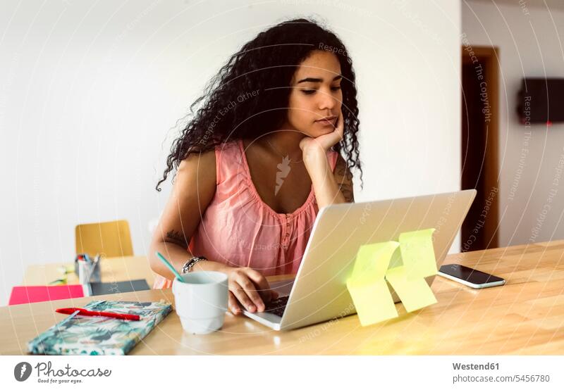 Junge Frau, die von zu Hause aus mit einem Laptop arbeitet Leute Menschen People Person Personen Alleinstehende Alleinstehender Singles Unverheiratete