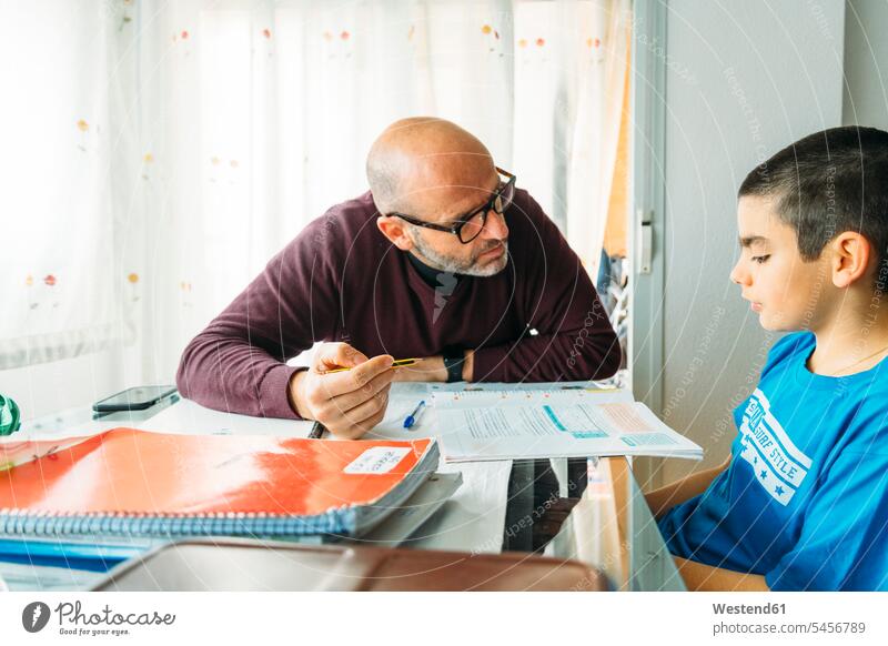 Vater erklärt Sohn, der während des Hausunterrichts am Schreibtisch sitzt Farbaufnahme Farbe Farbfoto Farbphoto Innenausstattung Wohnraum Wohnungseinrichtung