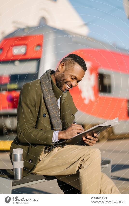 Porträt eines stilvollen Geschäftsmannes mit wiederverwendbarer Tasse und Dokumenten, die auf den Zug warten Job Berufe Berufstätigkeit Beschäftigung Jobs