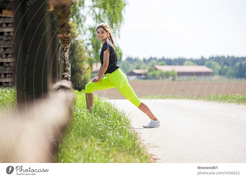 Frau macht Dehnungsübungen am Straßenrand Stretching dehnen strecken stretchen Dehnübung Fitness fit Gesundheit gesund Training trainieren Beweglichkeit