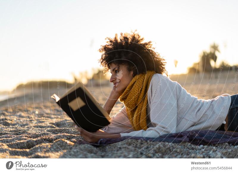 Frau, die im Sand liegt, sich am Strand entspannt und ein Buch liest Entspannung Entspannen relaxen entspannen Frau mittleren Alters Frauen mittleren Alters