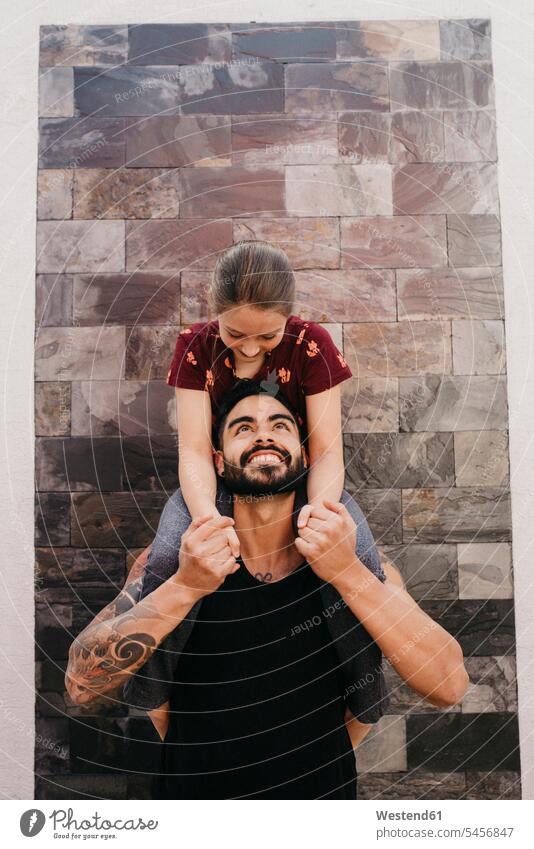 Vater trägt Tochter auf der Schulter, während er an der Wand steht Farbaufnahme Farbe Farbfoto Farbphoto Außenaufnahme außen draußen im Freien Tag