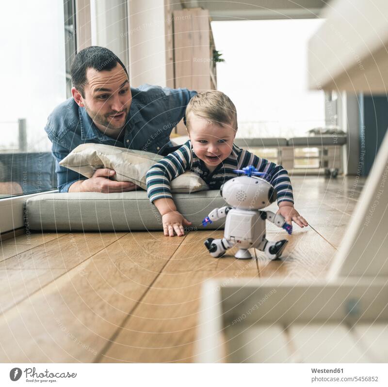 Aufgeregter Vater und Sohn liegen auf einer Matratze zu Hause und beobachten einen Spielzeugroboter Zuhause daheim liegend liegt Aufregung aufregend