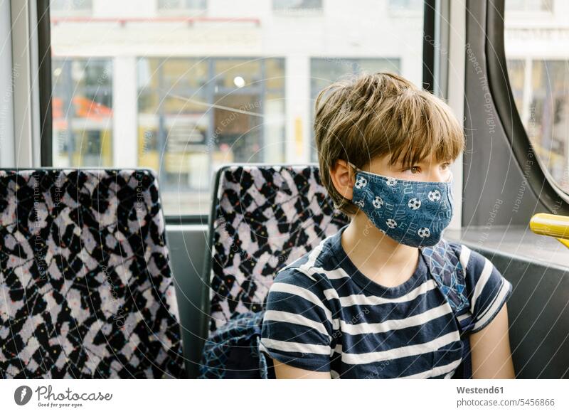 Junge mit Schutzmaske in der Strassenbahn Bälle Fussball Fußbälle Bahnen Straßenbahnen Tram Trambahn sitzend sitzt blaue blauer blaues hygienisch geschützt