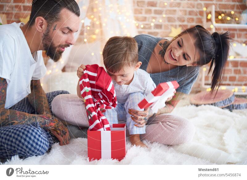 Junge öffnet Weihnachtsgeschenk mit seinen Eltern im Bett Weihnachtsgeschenke öffnen oeffnen Familie Familien Weihnachtszeit Weihnachten Christmas X-Mas X mas