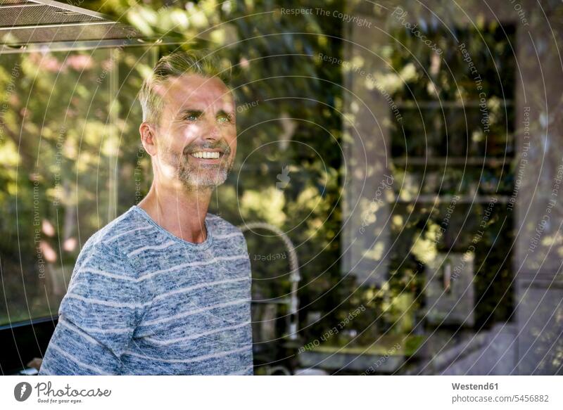 Porträt eines lächelnden reifen Mannes hinter einer Fensterscheibe zu Hause Zuhause daheim Fensterscheiben Portrait Porträts Portraits Männer männlich