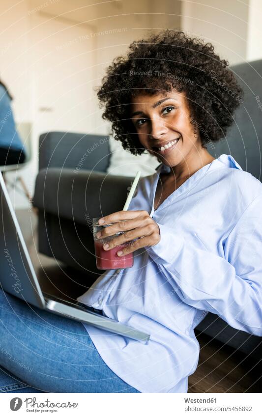 Porträt einer lächelnden Frau mit Softdrink auf dem Boden sitzend mit Laptop Böden Boeden Erfrischungsgetränk Erfrischungsgetraenk glücklich Glück
