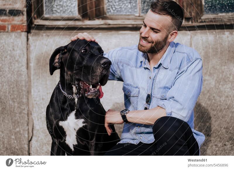Lächelnder Mann streichelt seinen Hund im Freien Leute Menschen People Person Personen Europäisch Kaukasier kaukasisch 1 Ein ein Mensch nur eine Person single