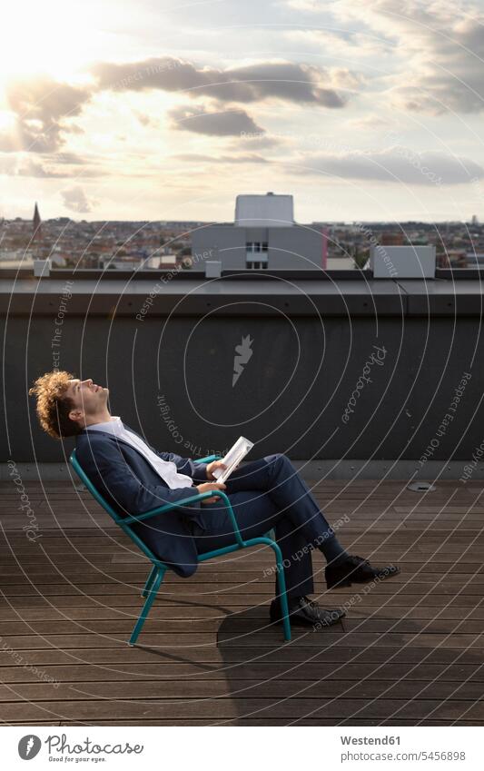 Deutschland, Berlin, Geschäftsmann entspannt auf Dachterrasse bei Sonnenuntergang Businessmann Businessmänner Geschäftsmänner Dachterrassen Sonnenuntergänge