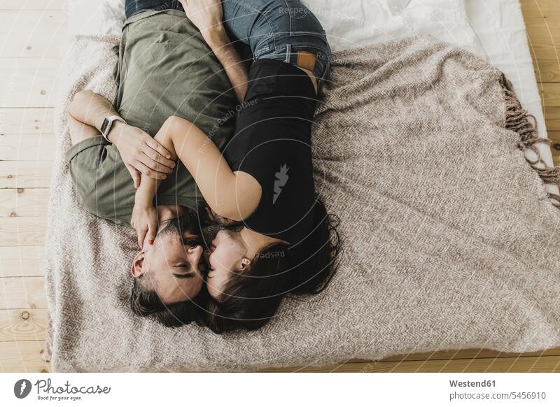 Paar auf dem Bett liegend, küssend, kuschelnd und umarmend Betten Zuhause zu Hause daheim Pärchen Paare Partnerschaft Umarmung Umarmungen Arm umlegen Küsse Kuss