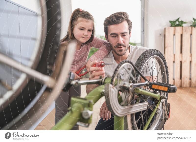 Junger Mann und kleines Mädchen reparieren Fahrrad zusammen Deutschland alleinerziehender Vater zeigen vorführen präsentieren Vorführung herzeigen