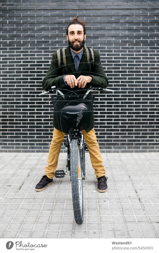 Porträt eines lächelnden Mannes mit E-Bike an einer Backsteinmauer Portrait Porträts Portraits Fahrrad Bikes Fahrräder Räder Rad eBikes E-Bikes Elektrofahrrad