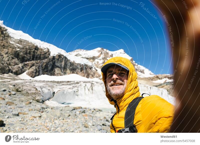 Lächelnder Mann nimmt Selbstvertrauen gegen schneebedeckten Berg Farbaufnahme Farbe Farbfoto Farbphoto Schweiz Berninagruppe Gebirge Gebirgslandschaft