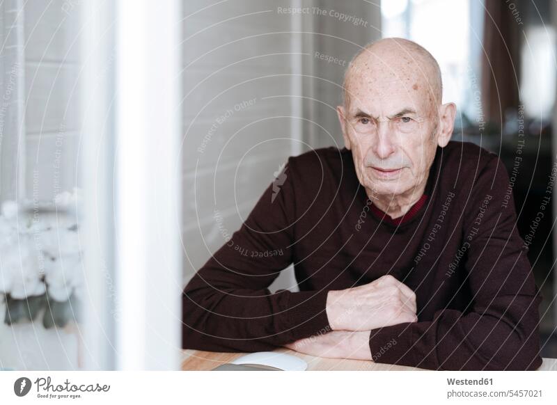 Porträt eines nachdenklichen alten Mannes, der am Tisch sitzt und aus dem Fenster schaut Leute Menschen People Person Personen Europäisch Kaukasier kaukasisch 1