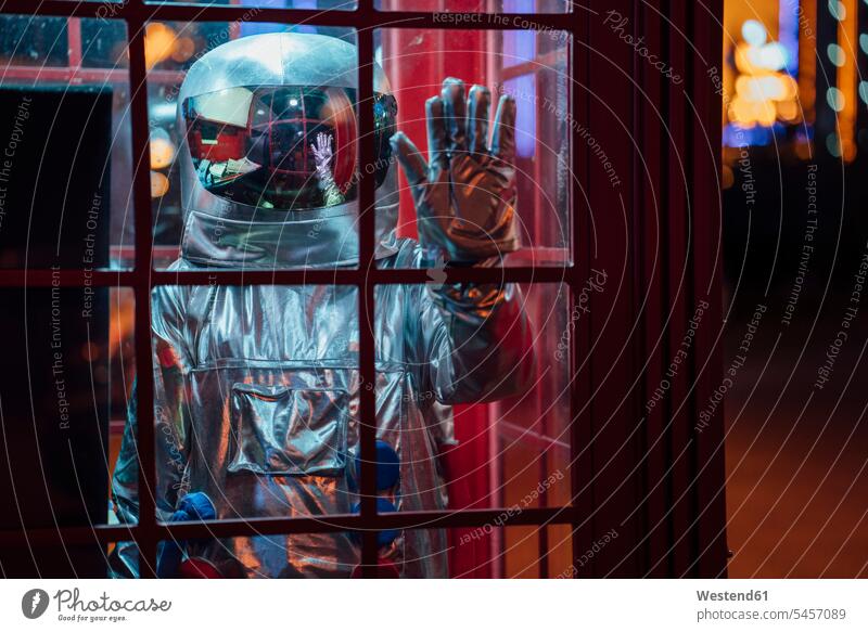 Raumfahrer, der nachts in einer Telefonzelle steht Telefonzellen Telefonhaeuschen Telefonhäuschen Astronaut Astronauten stehen stehend Nacht Weltraumfahrer