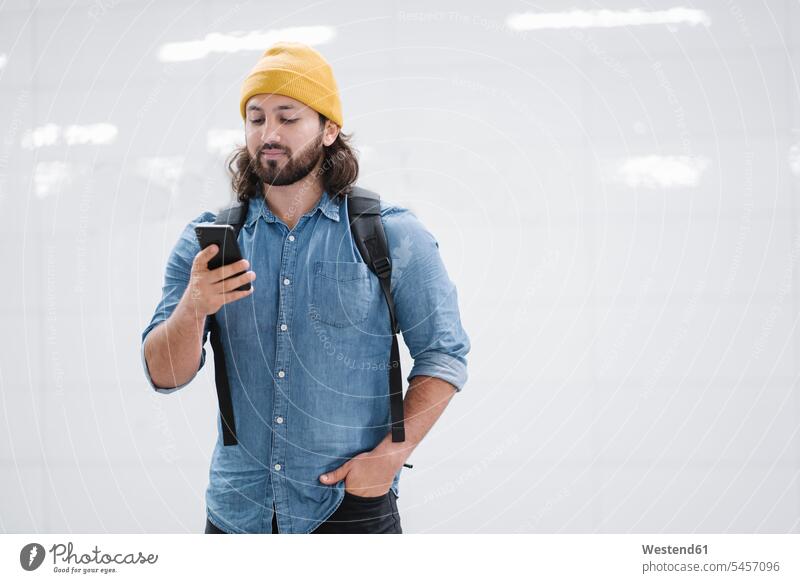 Porträt eines Mannes mit Rucksack beim Blick auf ein Smartphone Leute Menschen People Person Personen Personen aus dem Nahen Osten 1 Ein ein Mensch
