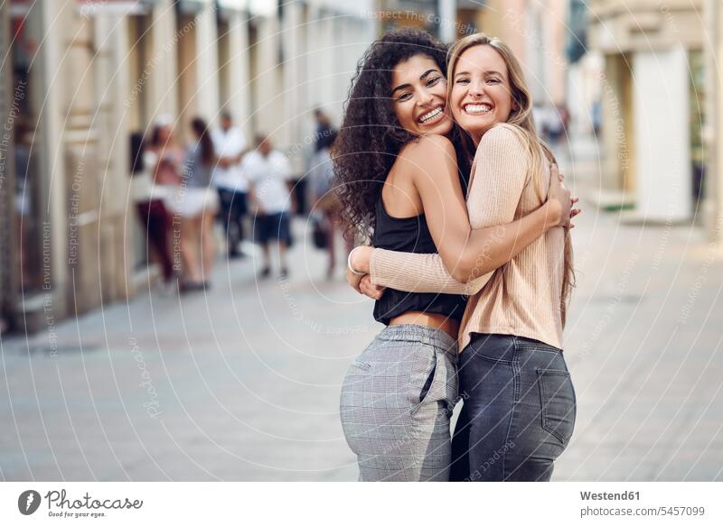 Porträt von zwei glücklichen Freunden, die sich auf der Straße umarmen Freundinnen Glück glücklich sein glücklichsein Portrait Porträts Portraits Umarmung