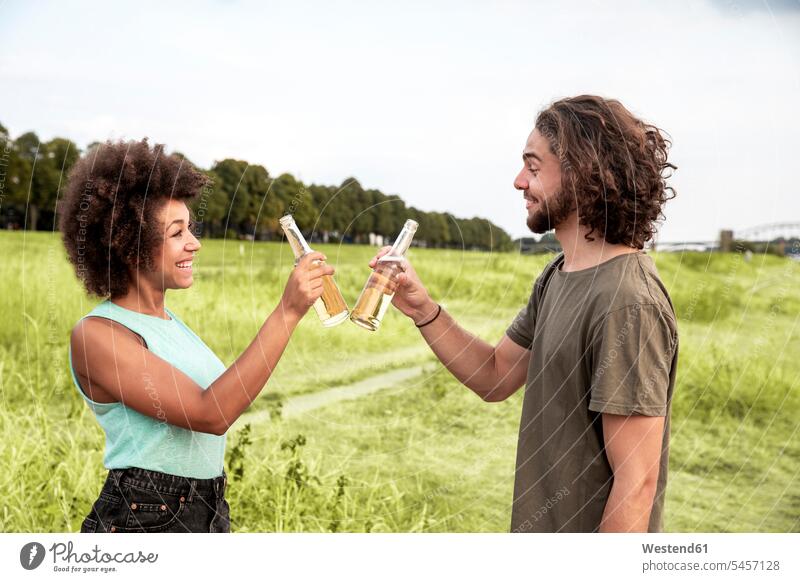 Glückliches Paar stößt mit Bierflaschen in der Natur an glücklich glücklich sein glücklichsein Pärchen Paare Partnerschaft anstoßen zuprosten anstossen Flasche