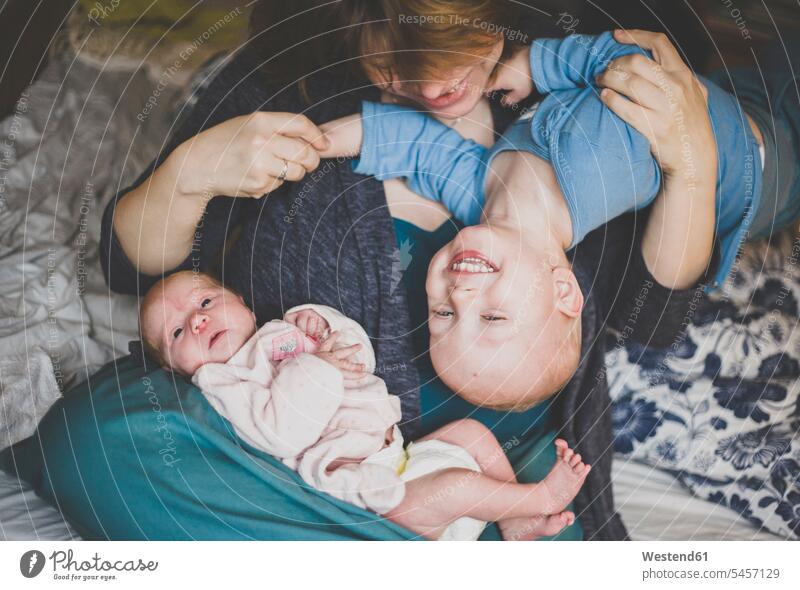Mutter spielt mit einem Kleinkindsohn und einer neugeborenen Tochter Betten begeistert Enthusiasmus enthusiastisch Überschwang Überschwenglichkeit freuen