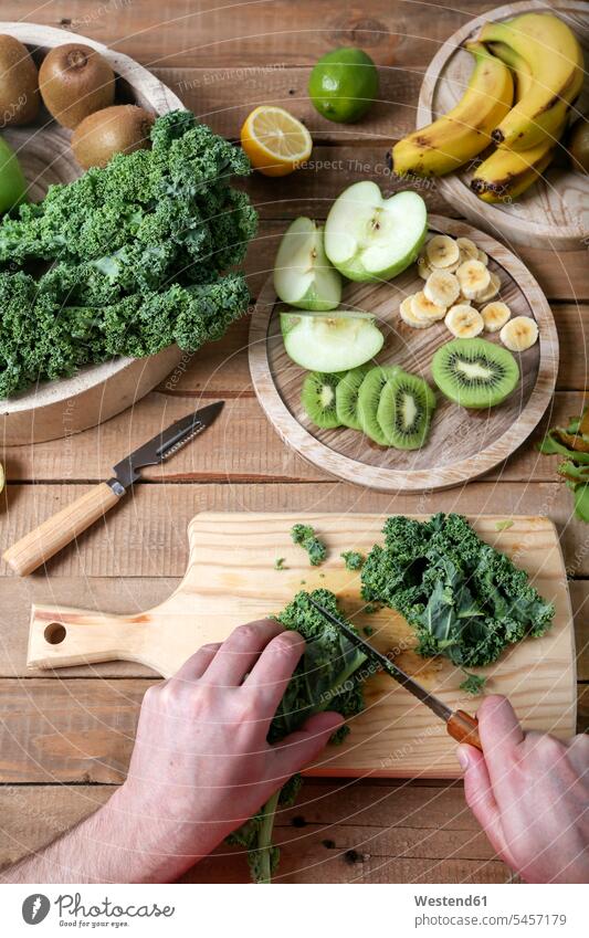 Mann bereitet grünen Smoothie vor und schneidet Grünkohl Zubereitung zubereiten Zutaten schneiden Küchenmesser Ingwerwurzel Ingwerwurzeln vitaminreich Vitamine