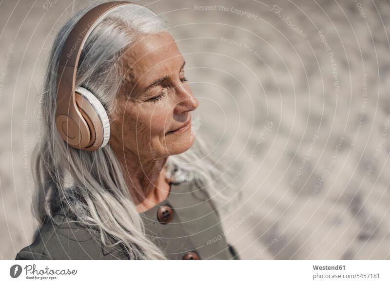 Ältere Frau hört Musik mit Kopfhörern am Strand Leute Menschen People Person Personen Europäisch Kaukasier kaukasisch 1 Ein ein Mensch eine nur eine Person