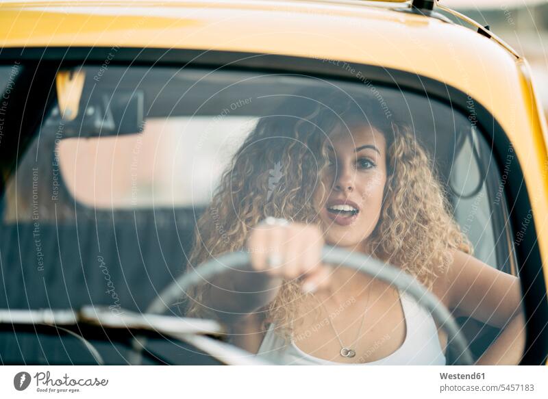 Porträt einer überraschten blonden Frau, die einen Oldtimer fährt weiblich Frauen erstaunt verwundert verblüfft fahren fahrend fahrender fahrendes blonde Haare