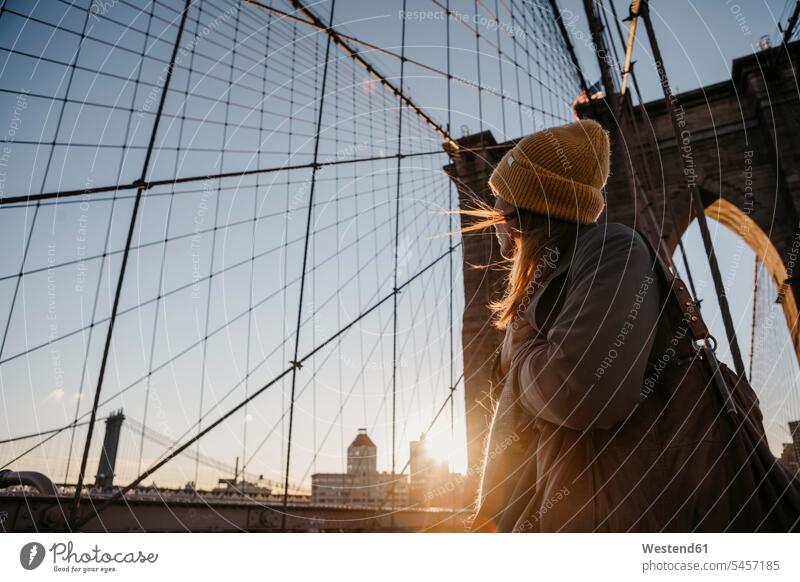 USA, New York, New York City, weiblicher Tourist auf Brooklyn Bridge bei Sonnenaufgang Frau Frauen entdecken Sonnenaufgänge Touristin Reisende Reisender morgens