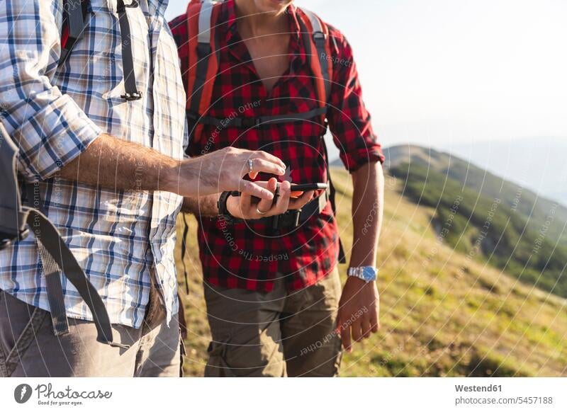 Italien, Monte Nerone, Nahaufnahme von zwei Männern beim Wandern und mit Smartphone in den Bergen Handy Mobiltelefon Handies Handys Mobiltelefone Gebirge