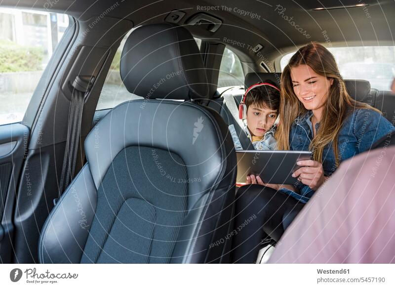 Familie auf Autoreise mit Mutter und Sohn bei Tablettentausch fahren fahrend fahrender fahrendes Wagen PKWs Automobil Autos Tablet Computer Tablet-PC Tablet PC