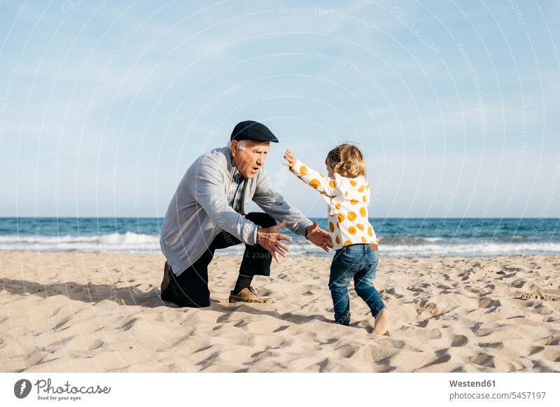 Großvater spielt mit seiner Enkelin am Strand Urgroßvater Uropa Uropas Urgroßväter Sandstrand Sandstrände Sandstraende Meer Meere laufen rennen Bewegung