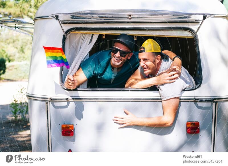 Schwule Männer mit Regenbogenfahne genießen im Wohnmobil Farbaufnahme Farbe Farbfoto Farbphoto Spanien Freizeitbeschäftigung Muße Zeit Zeit haben
