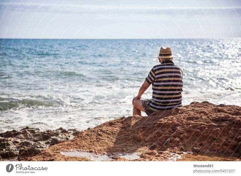 Italien, Sizilien, Cava D'aliga, älterer Mann sitzt an der Küste und schaut aufs Meer Meere schauen sehend Kueste Kuesten Küsten Männer männlich sitzen sitzend