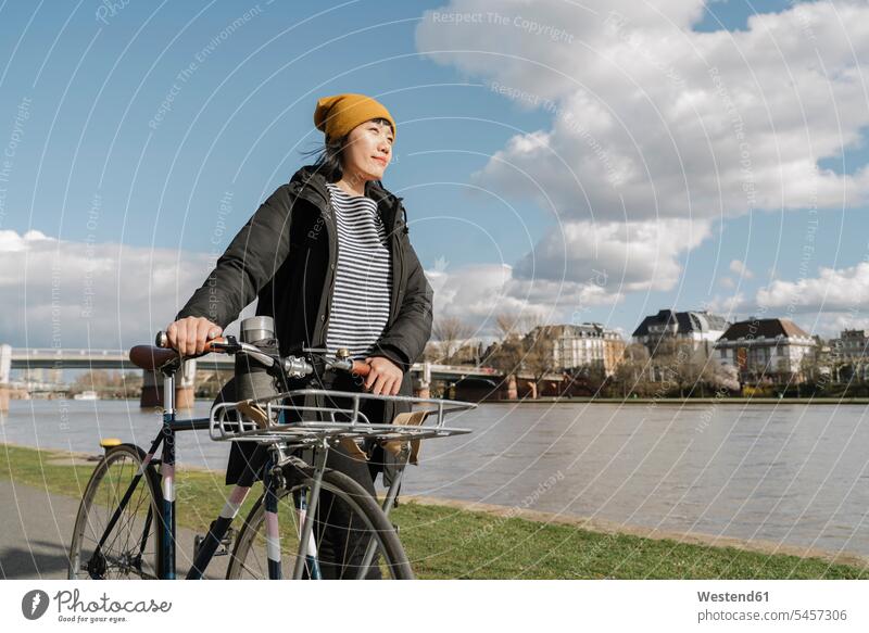 Frau mit Fahrrad am Flussufer, Frankfurt, Deutschland Transport Transportwesen Raeder Räder Bike Bikes Fahrräder Rad gehend geht verreisen zufrieden erforschen