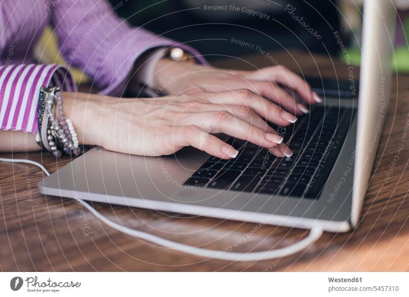 Hände einer Geschäftsfrau mit Laptop auf dem Schreibtisch im Büro Farbaufnahme Farbe Farbfoto Farbphoto Innenaufnahme Innenaufnahmen innen drinnen