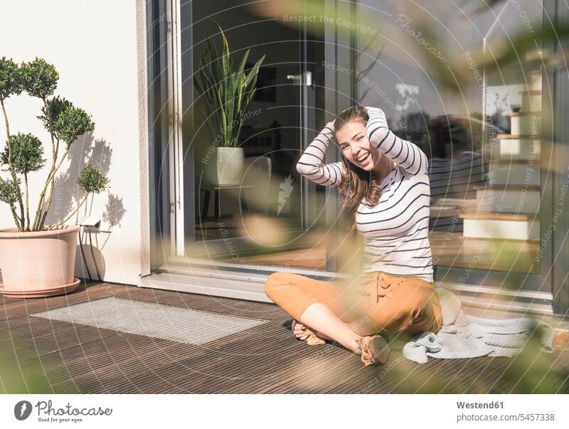 Porträt einer lachenden jungen Frau, die zu Hause auf der Terrasse sitzt barfuß nackte Füße nackter Fuss barfuessig barfüssig nackter Fuß barfuss barfüßig