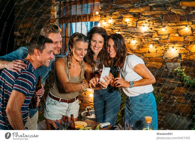 Glückliche Freunde treffen sich im Freien an einem Steinhaus und machen ein Selfie Kameradschaft Flaschen Bierflaschen Tische Telekommunikation telefonieren