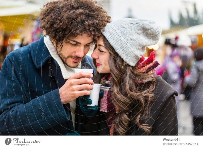 Glückliches, zärtliches junges Paar mit heißen Getränken auf dem Weihnachtsmarkt Zuneigung Pärchen Paare Partnerschaft glücklich glücklich sein glücklichsein