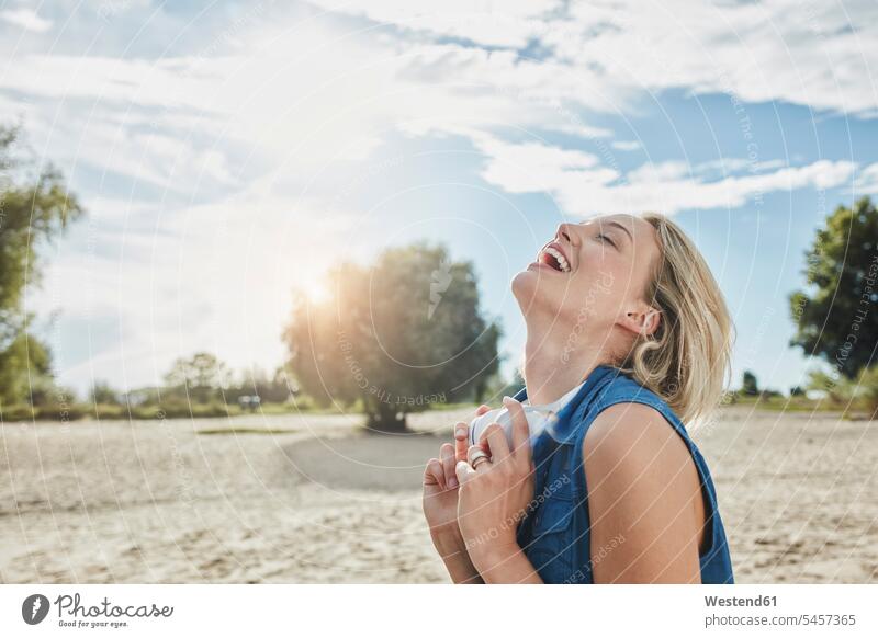 Glückliche junge Frau mit Kopfhörer am Strand Kopfhoerer weiblich Frauen glücklich glücklich sein glücklichsein Beach Straende Strände Beaches Erwachsener