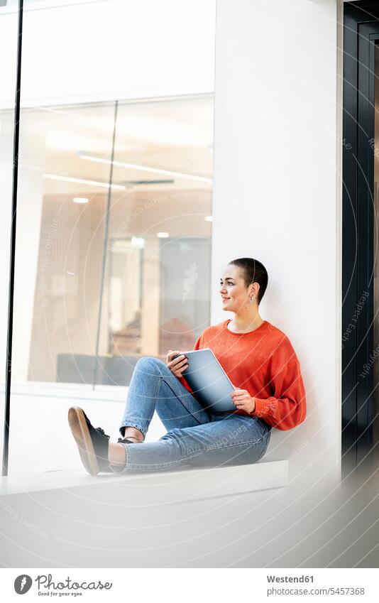 Entspannte Geschäftsfrau sitzt auf der Fensterbank eines Bürogebäudes und benutzt ein digitales Tablet Job Berufe Berufstätigkeit Beschäftigung Jobs