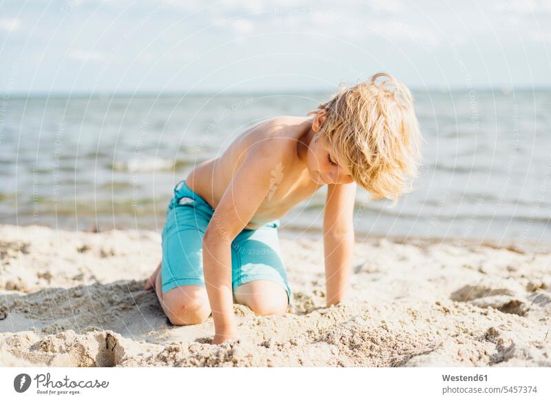 Blonder Junge spielt mit Sand am Strand Buben Knabe Jungen Knaben männlich sandig spielen Beach Straende Strände Beaches blond blonde Haare blondes Haar Kind