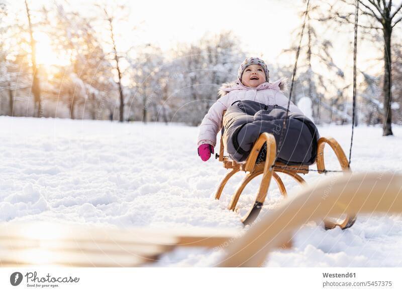 Glückliches Mädchen auf Schlitten in Winterlandschaft glücklich glücklich sein glücklichsein Winterlandschaften weiblich Landschaft Landschaften Kind Kinder