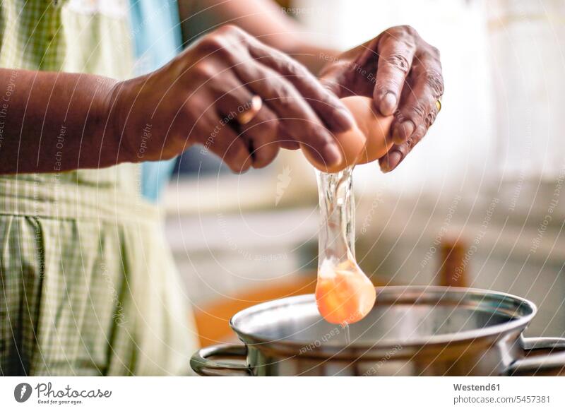 Hände einer Frau, die ein Ei aufschlägt Kochtopf Kochtöpfe Kochtoepfe Topf Töpfe weiblich Frauen Tradition Brauchtum traditionell zerbrechen auseinanderbrechen